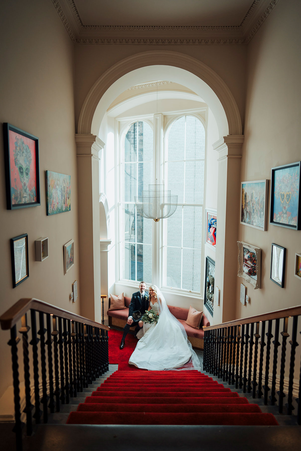 bride and groom set in front of tall window next to red carpet at Virgin Hotels Edinburgh wedding