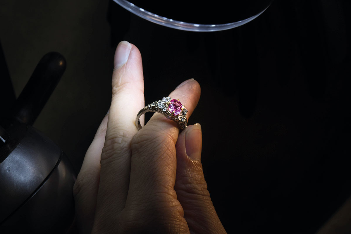 Bespoke pink gemstone engagement ring being inspected under a jeweller's work light