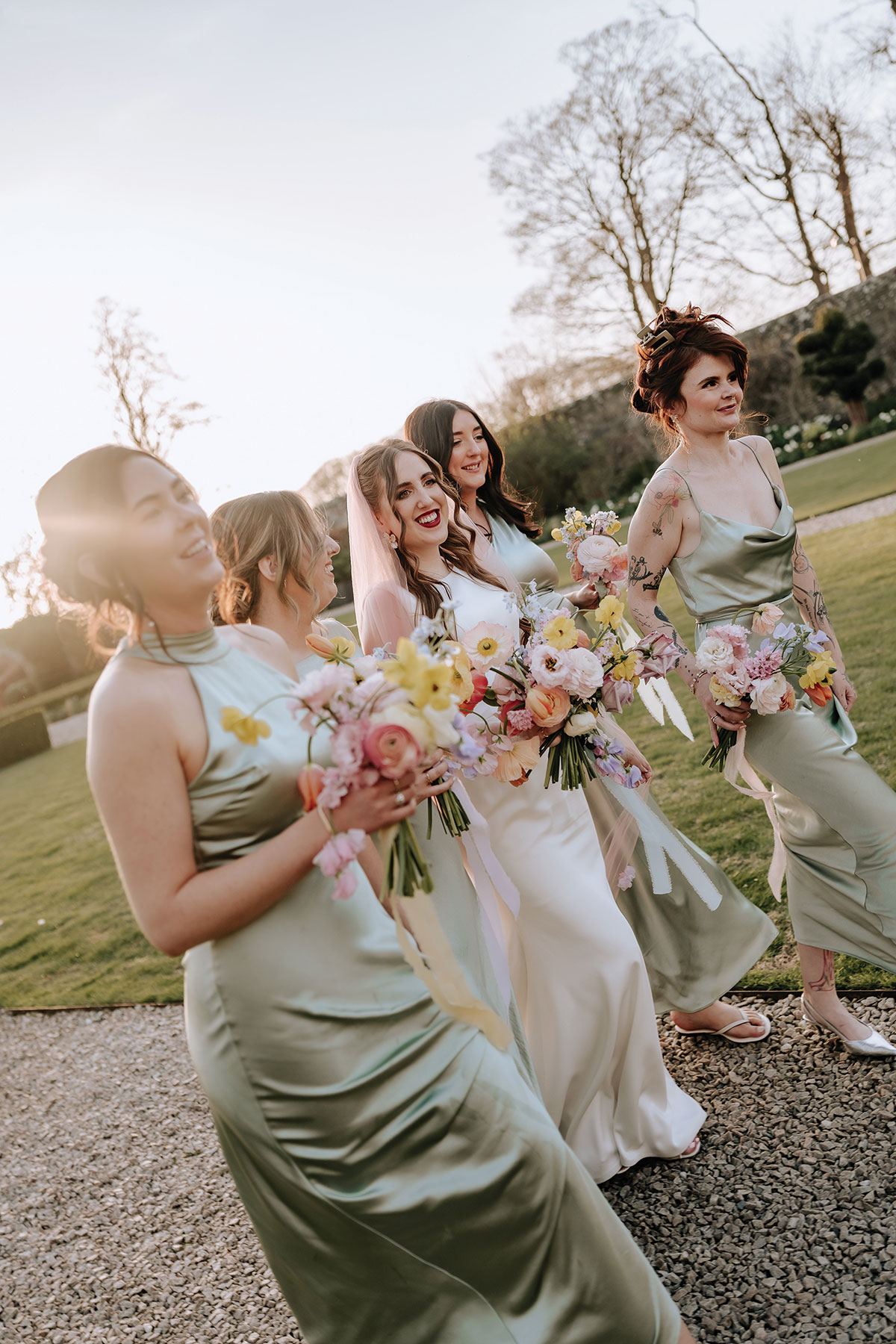 a bride and bridesmaids walking in gardens of Carlowrie Castle