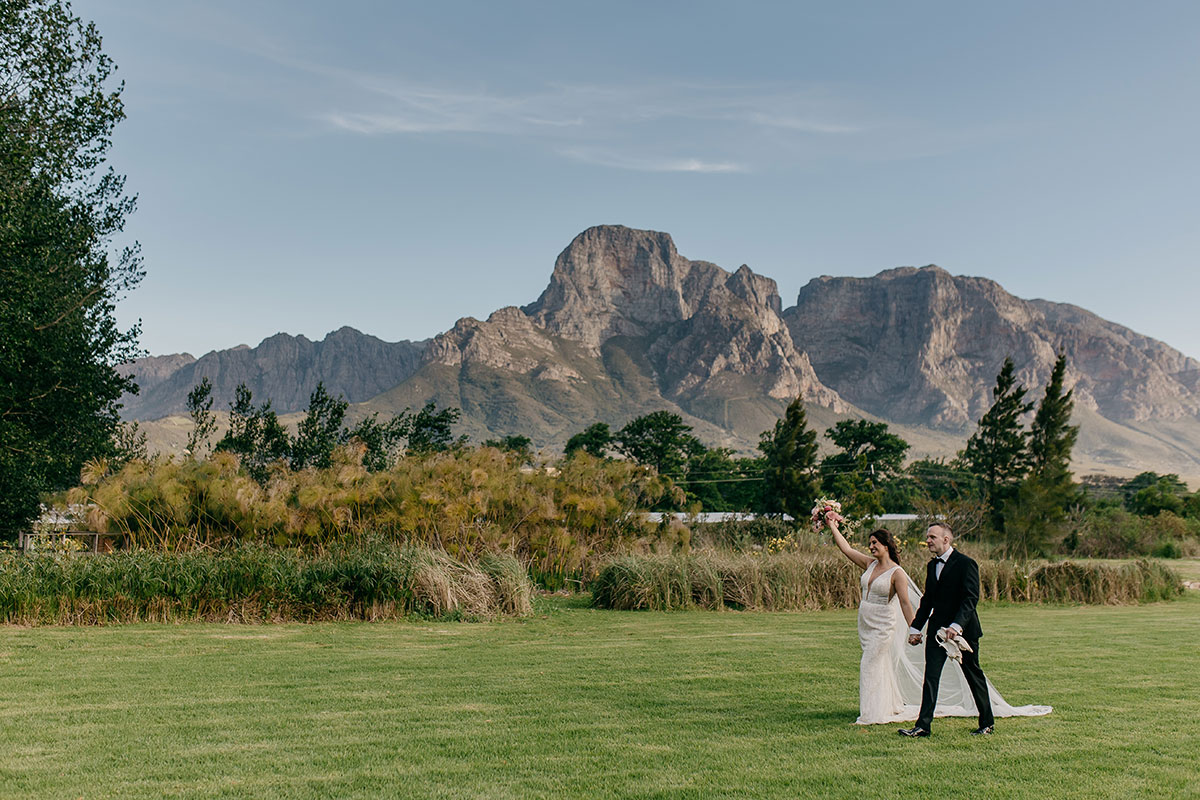 Bride and groom walking through the gardens at sunset during golden hour portraits at Boschendal Wine Estate wedding