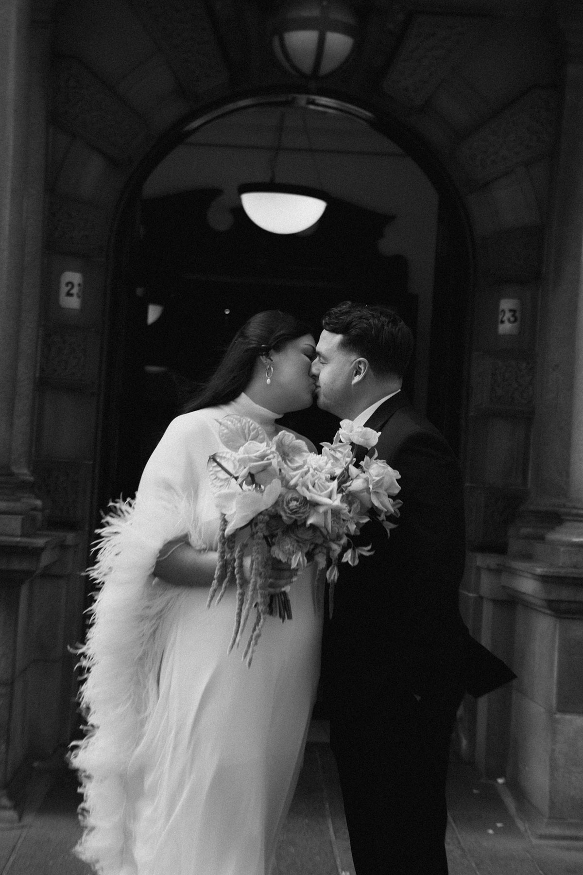 Black and white photo of bride and groom kissing outside their Glasgow wedding venue