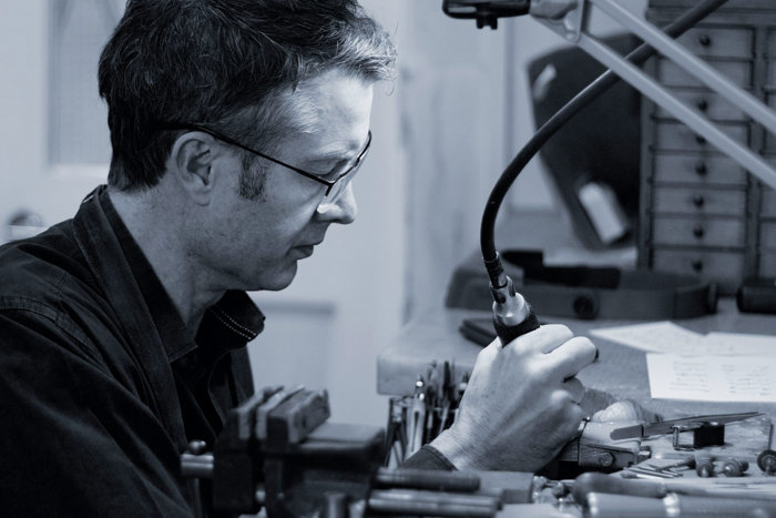Black and white photo of a man making jewellery at machine