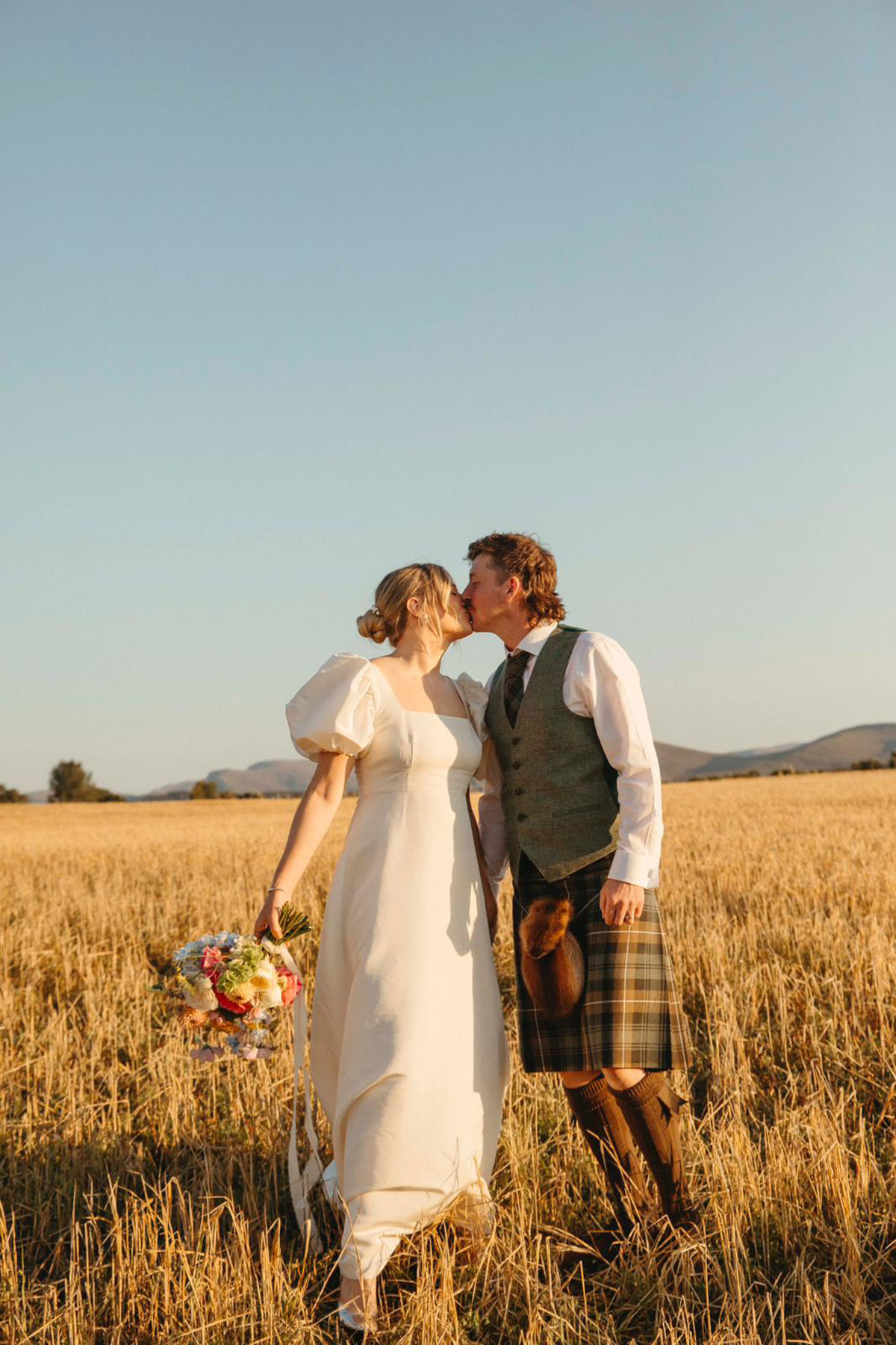 Bride and groom kiss in golden field during sunset wedding portraits in the Cairngorms Highlands
