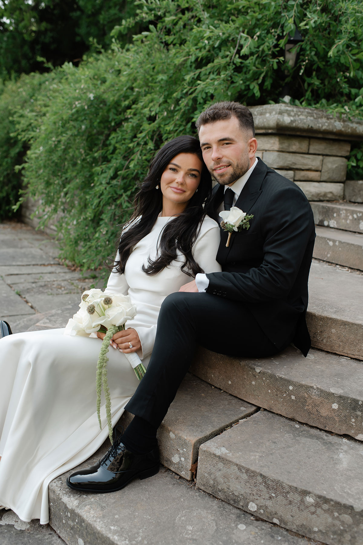 Bride and groom seated on stone steps at Carberry Tower after their small home wedding ceremony
