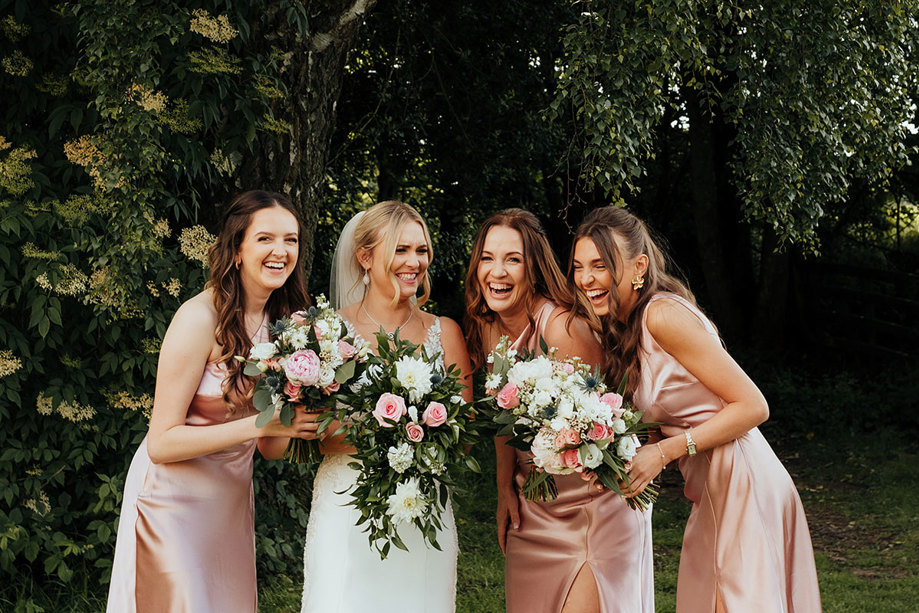 bride and bridesmaid standing side by side and laugh for photo at dalhousie castle