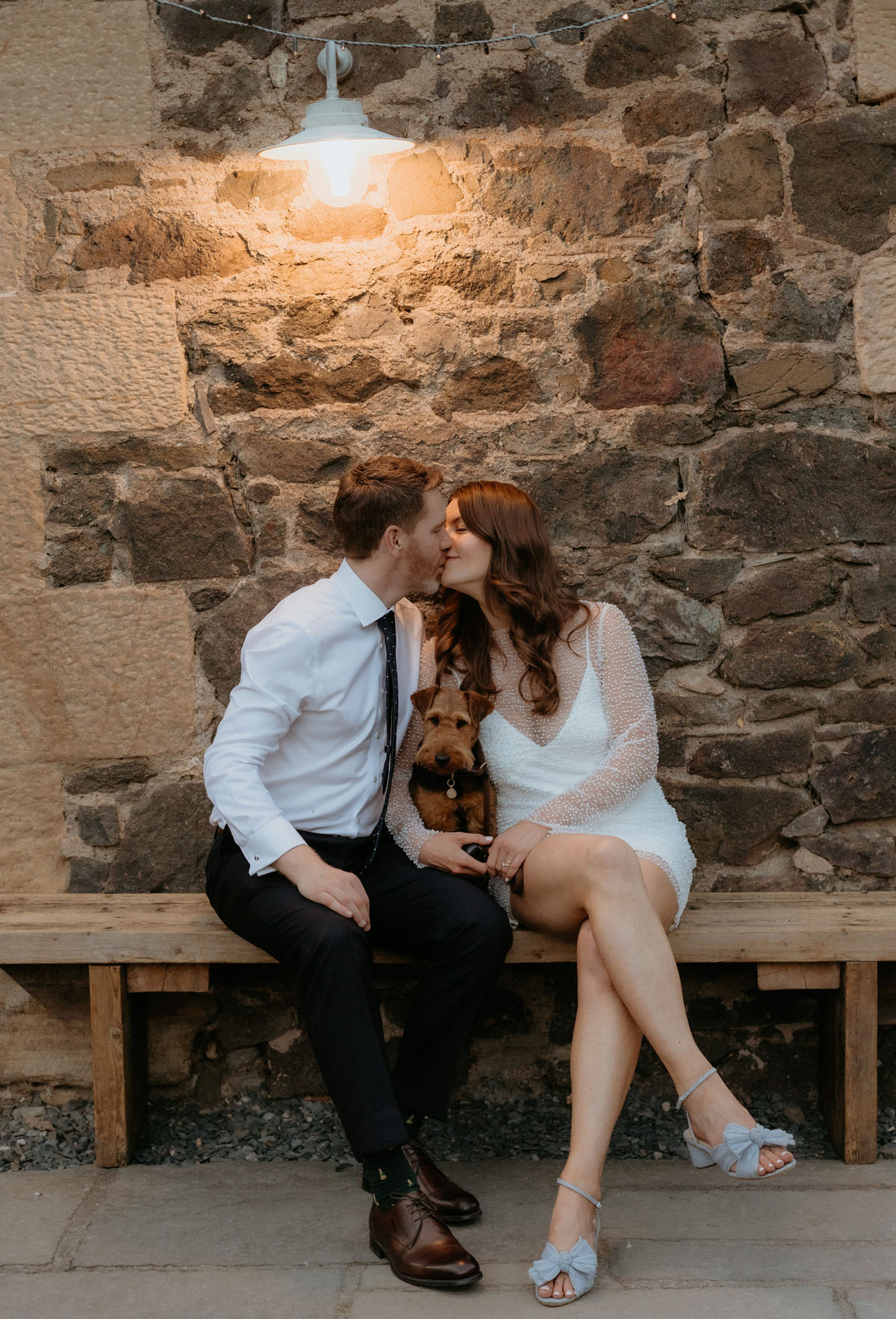 Newlyweds kissing with their dog between them during an evening portrait at The Byre at Inchyra in Perthshire.