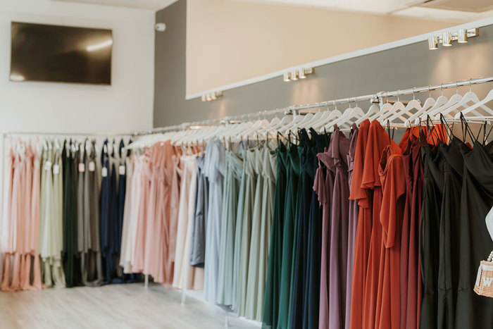 racks of bridesmaids dresses sorted by colour