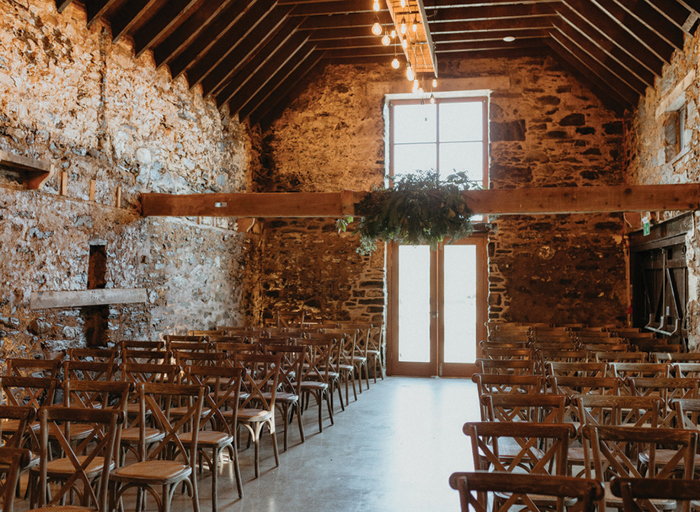 a brick-walled indoor space with rows of chairs set up with an aisle running down the middle of two sides