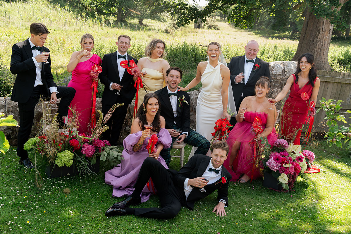 Bride and groom pose with guests in gardens of Kinkell Byre.