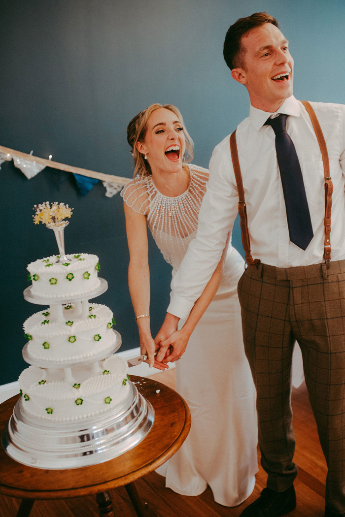 Bride and groom smile as they cut three tier cake at mar lodge