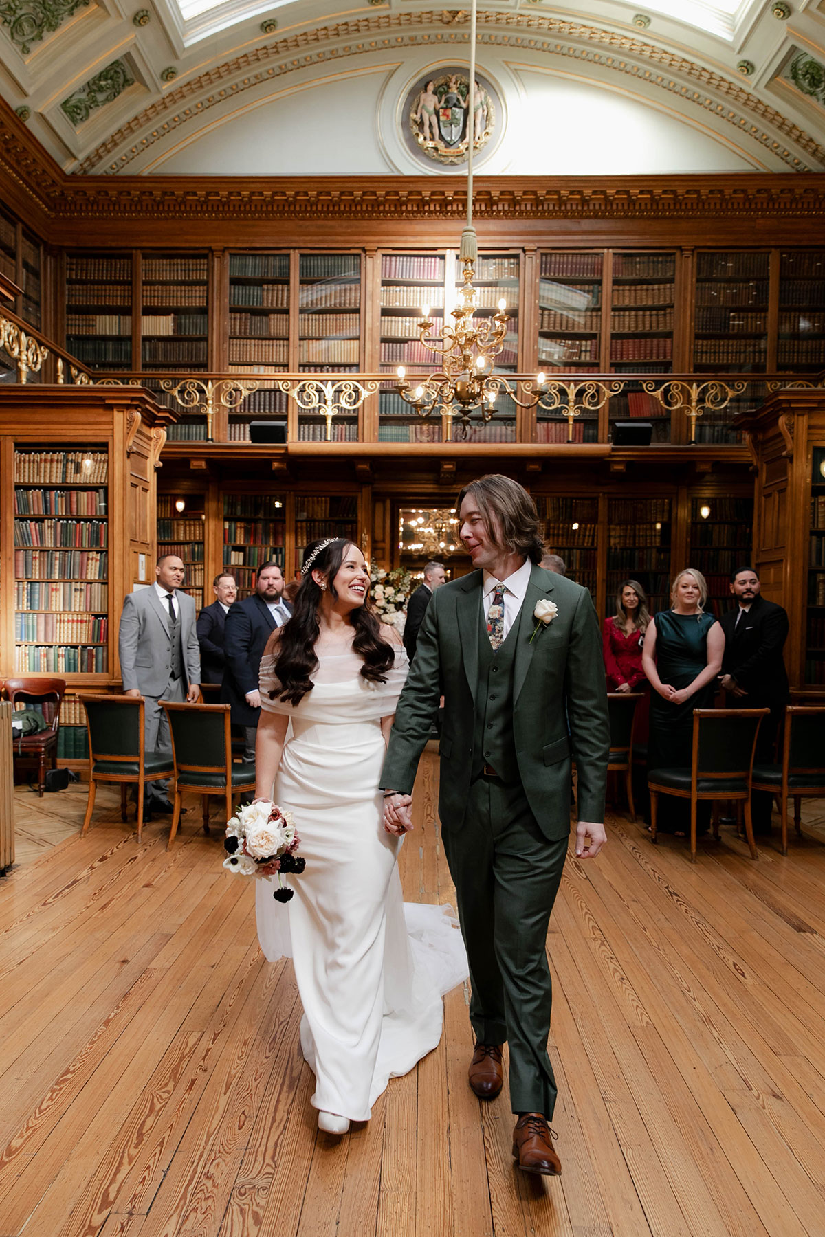 A bride and groom walking hand in hand up the aisle after their ceremony in the historic library at the Royal College of Physicians of Edinburgh
