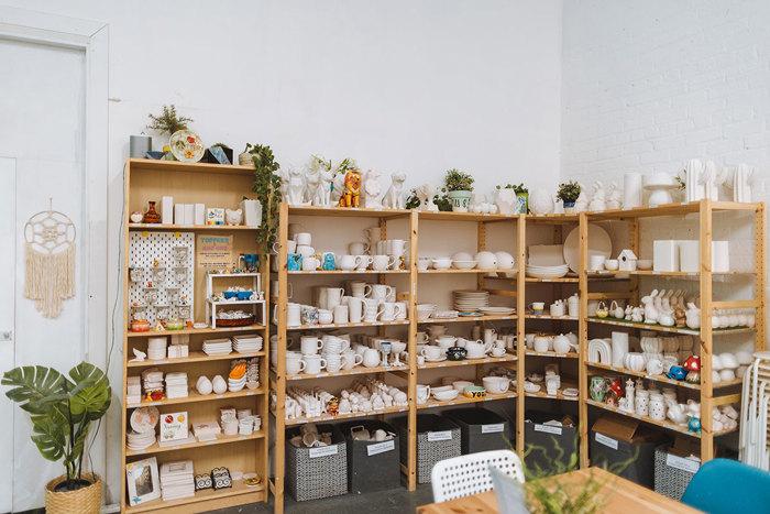 wooden shelving houses a wide assortment of ceramic pieces, from mugs and plates to figurines and vases