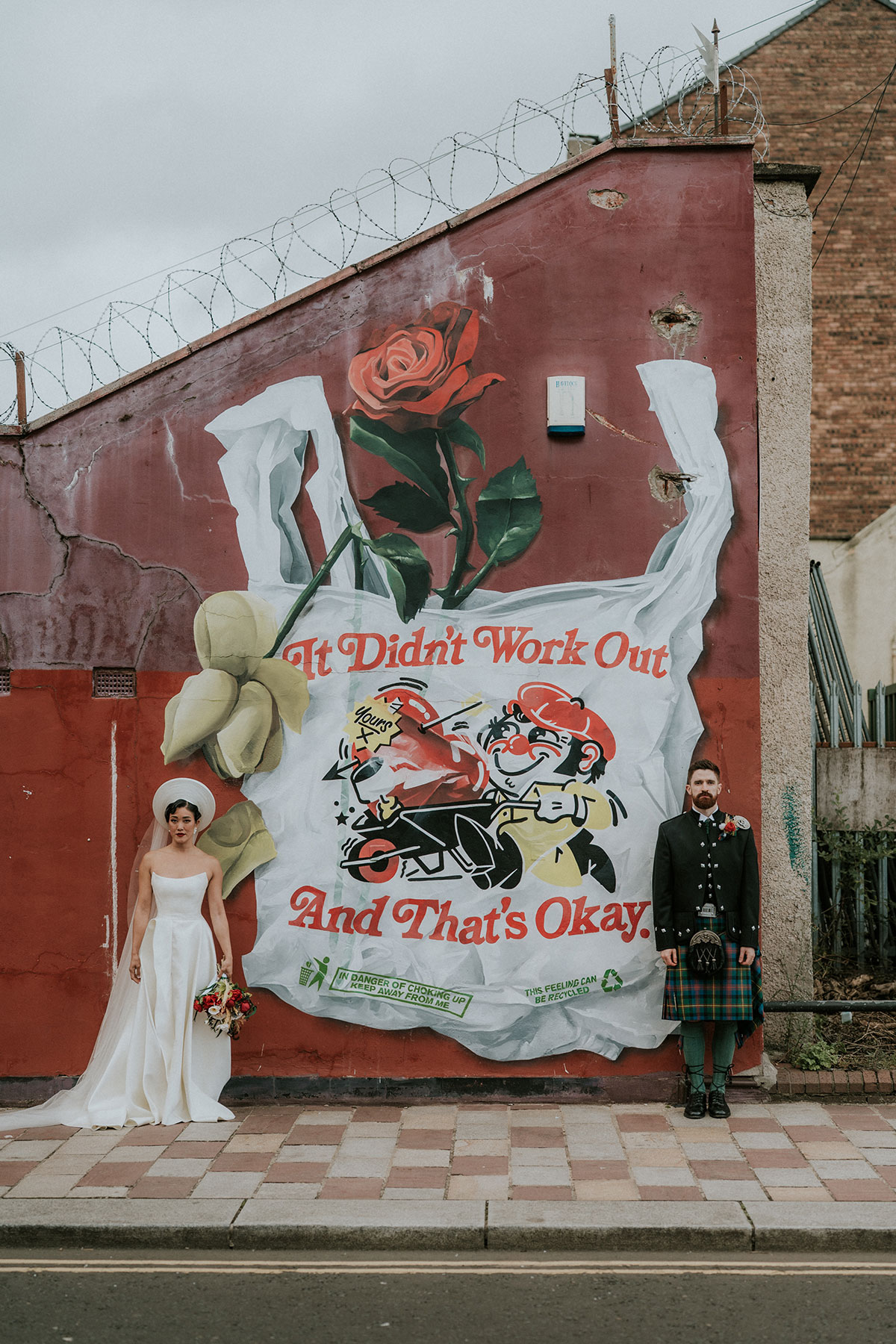 Bride and groom posing apart against large mural street art in Glasgow near BAaD wedding venue