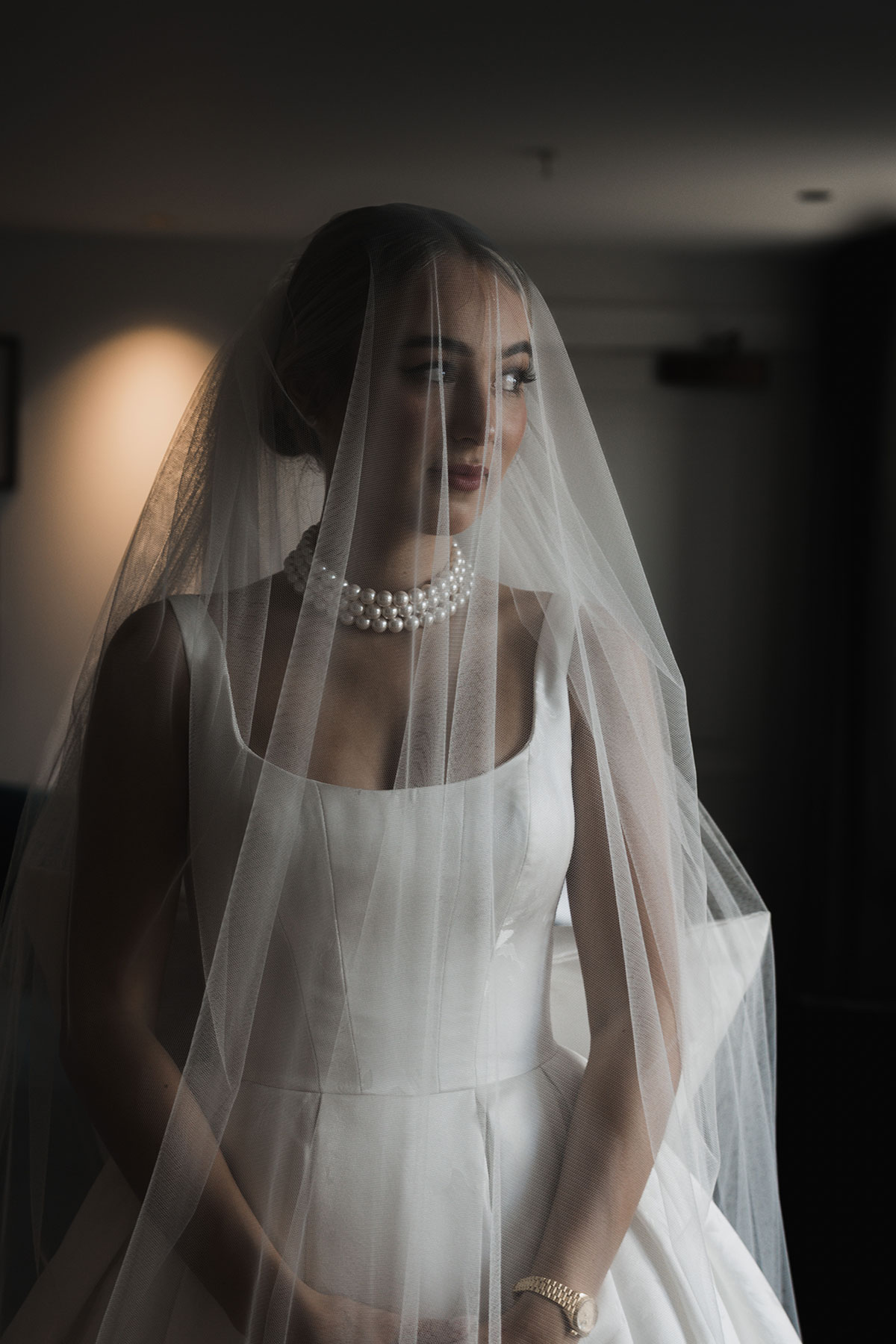 Bride in silk robe adjusting long tulle veil during morning preparations at Mansfield Traquair wedding