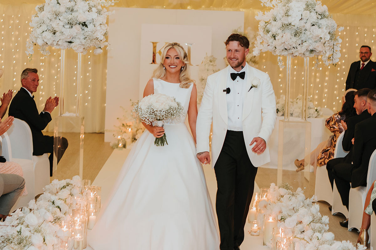 Bride and groom walking down candlelit aisle at Ingliston Estate and Country Club wedding ceremony in Scotland
