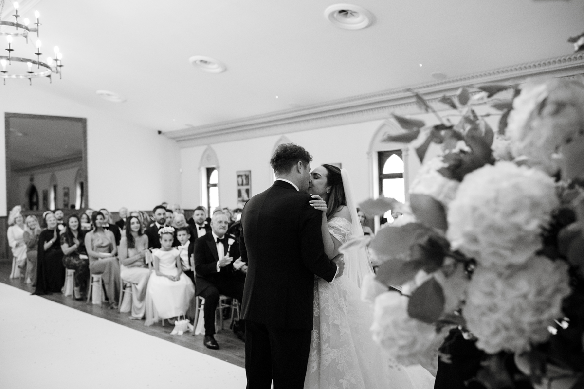 Bride and groom sharing their first kiss during their wedding ceremony at Crossbasket Castle near Glasgow.
