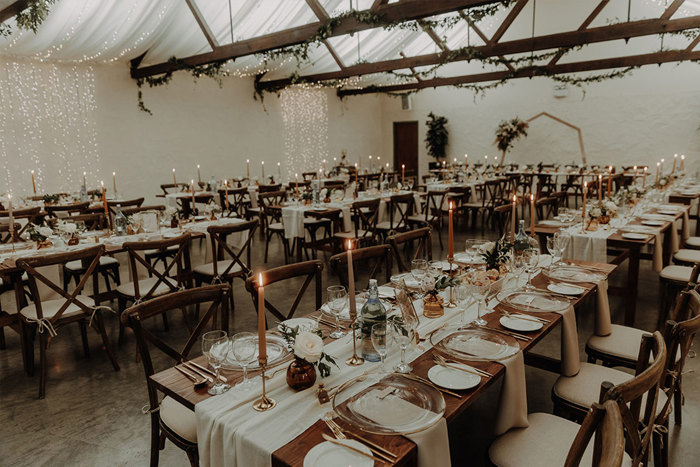 Inside a barn set for a wedding dinner with long tables
