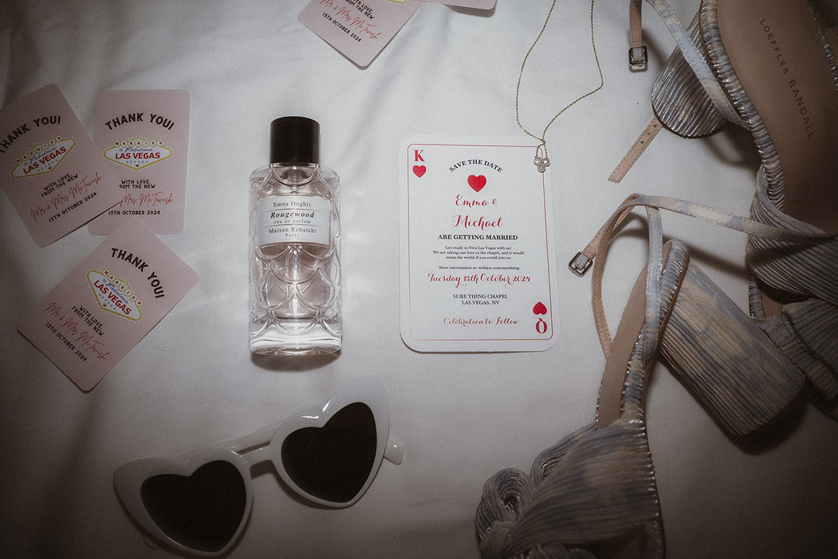 Flatlay of wedding items including perfume and playing cards