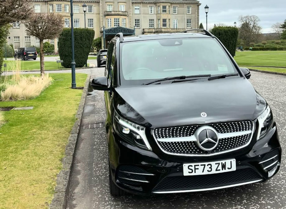 Black Mercedes Benz car parked in a garden in front of a stately home