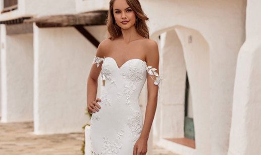 woman wearing a sweetheart neckline wedding dress including 3D floral detailing and decorative shoulder trailing straps