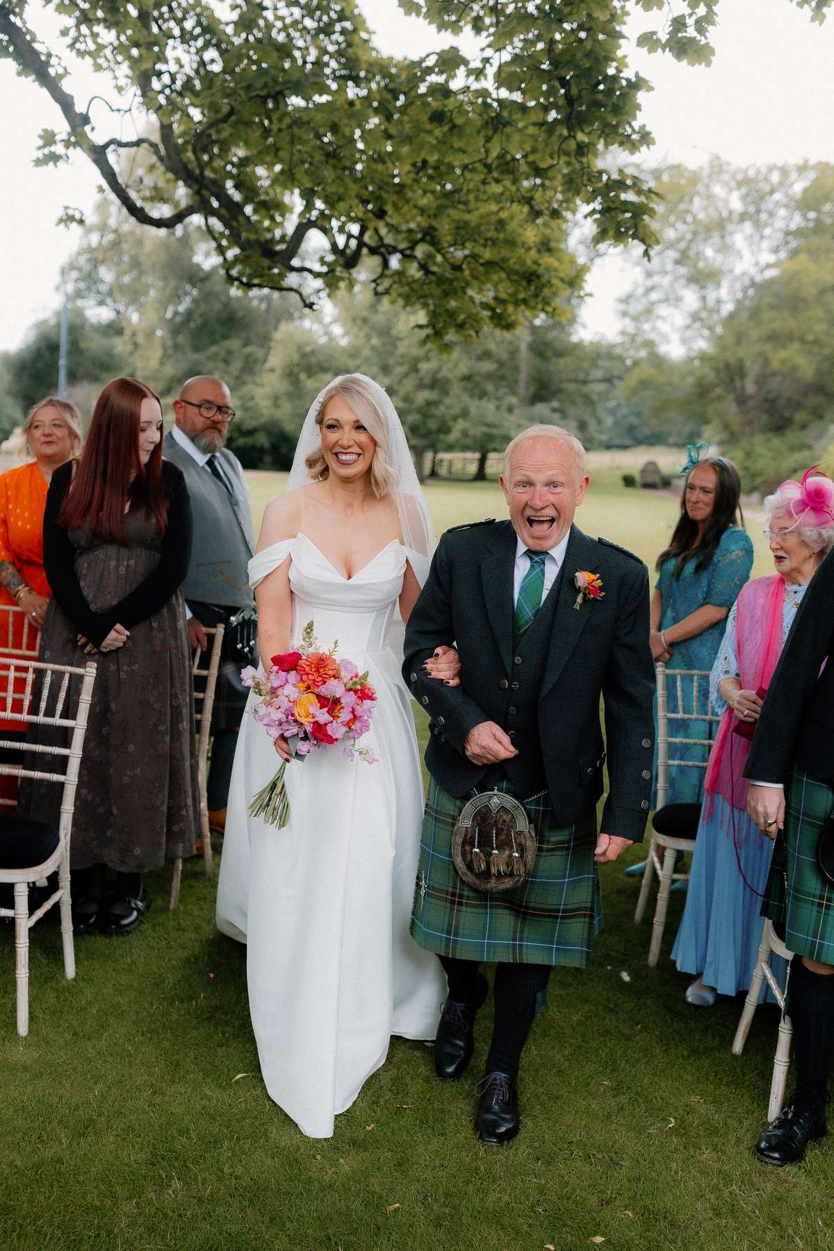 Bride Kara walks down the aisle with her dad during her outdoor wedding ceremony at Prestonfield House in Edinburgh.