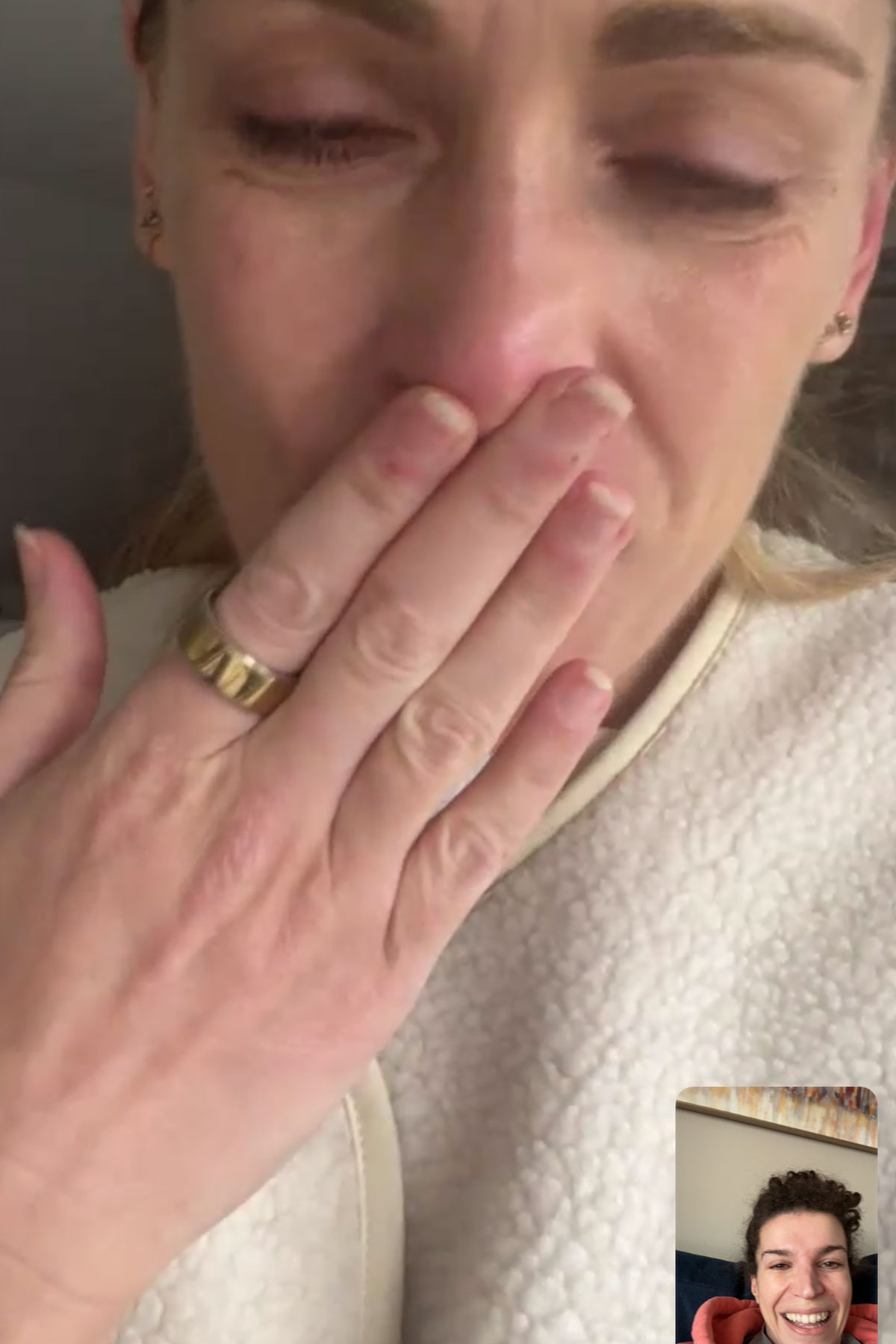 Bride crying during an emotional FaceTime call before her wedding while wearing a cosy white fleece