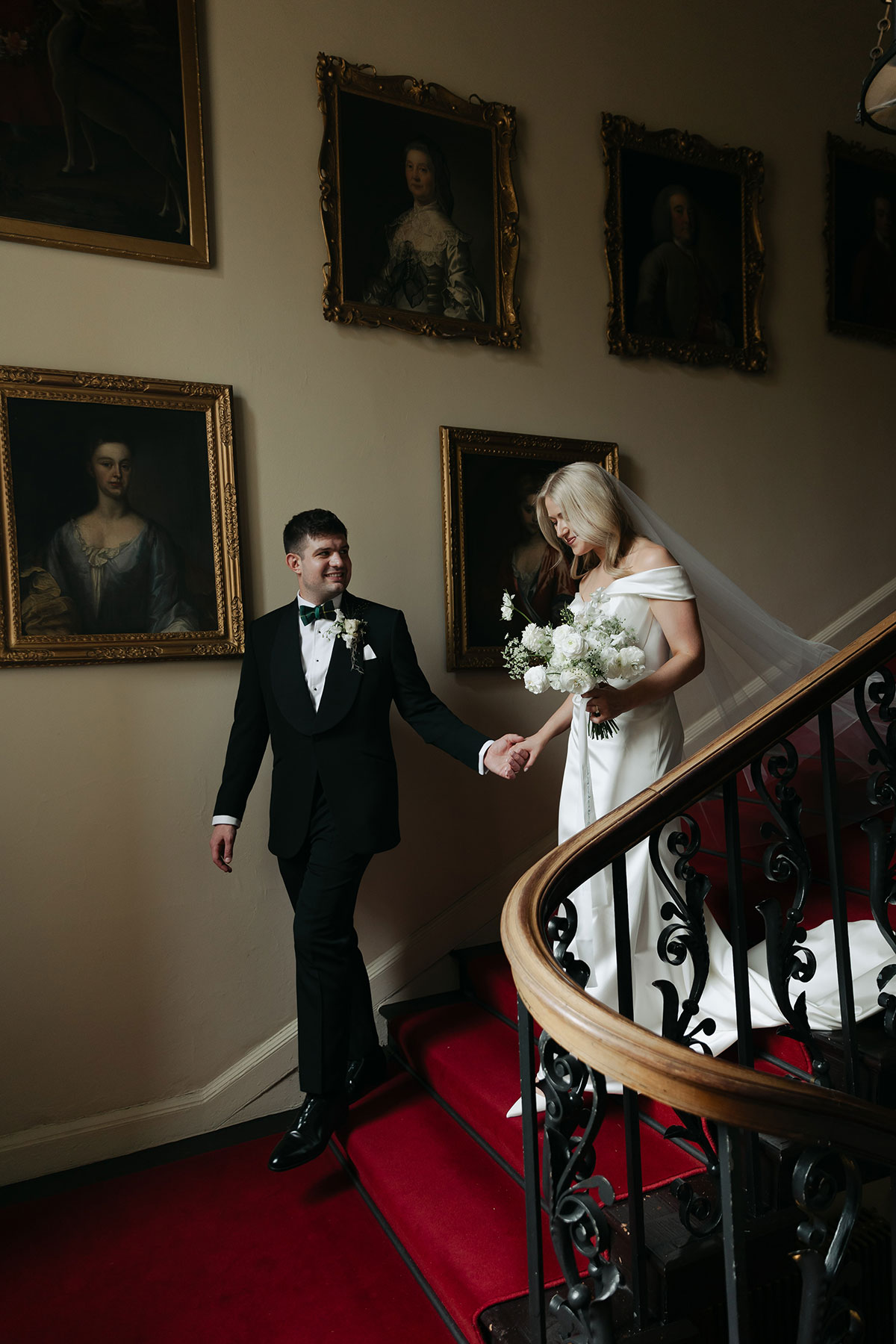 Bride and groom walking down grand staircase at Gilmerton House wedding venue in East Lothian