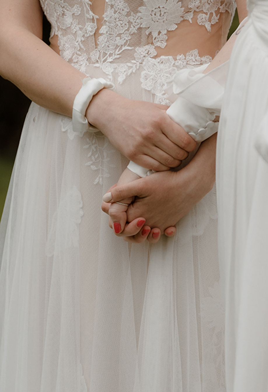 detail of two brides holding hands