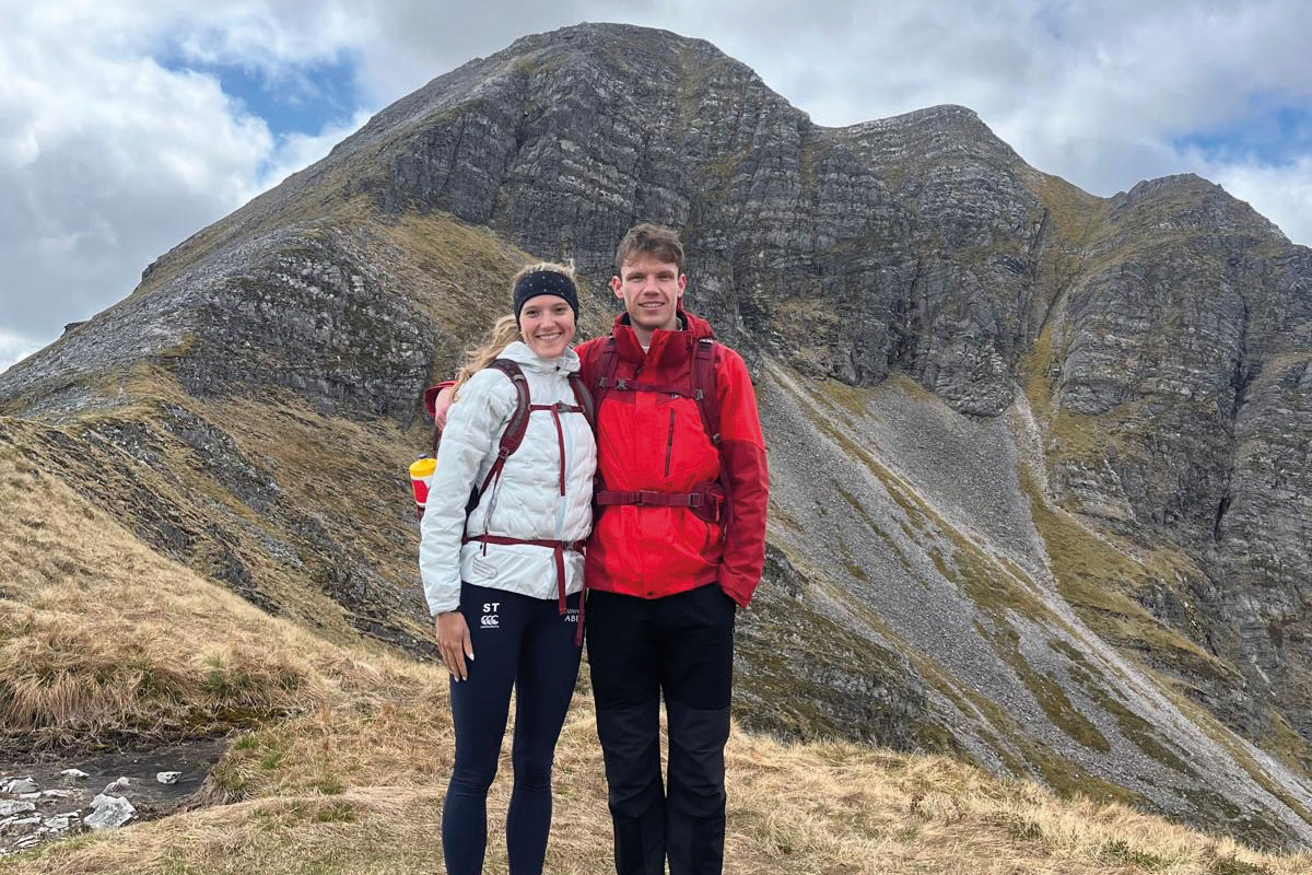 two people wearing hillwalking attire posing with a Scottish mountain in the background