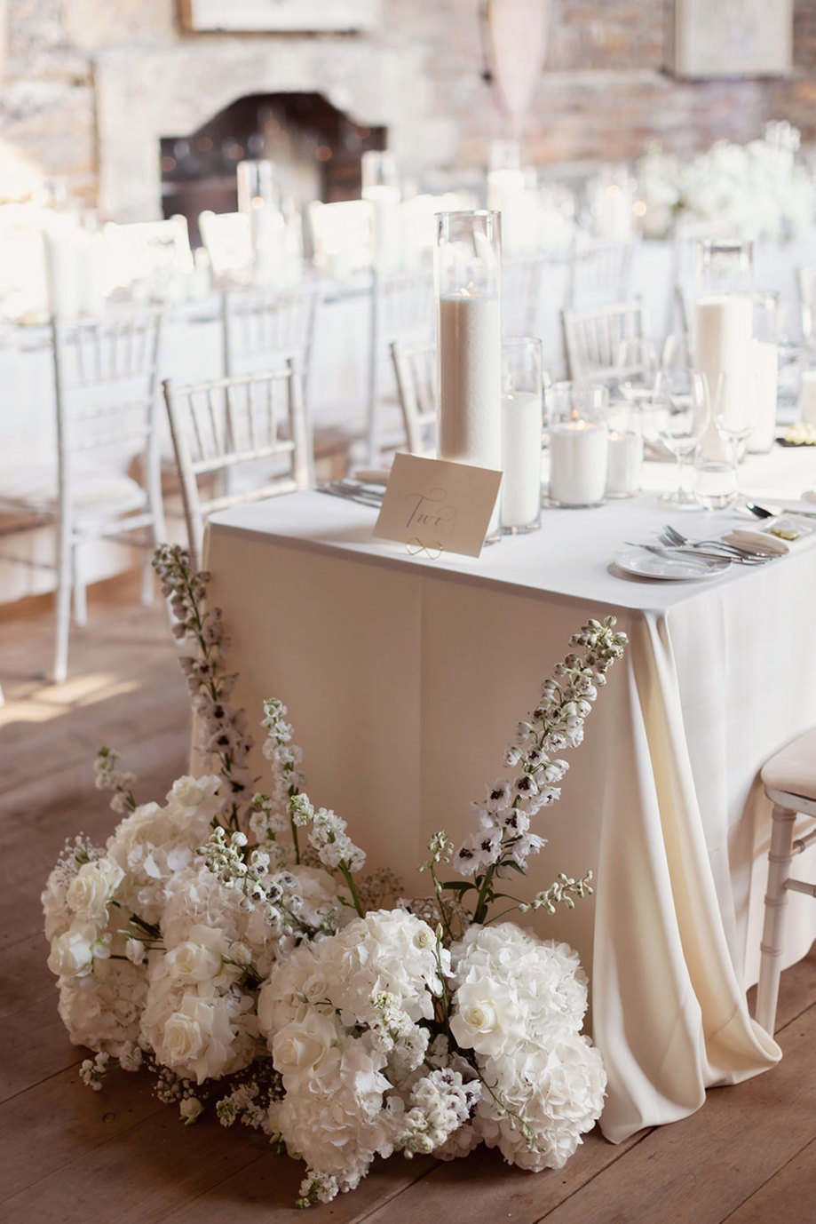 a wedding table with white hydrangea and rose floral arrangement on the floor.