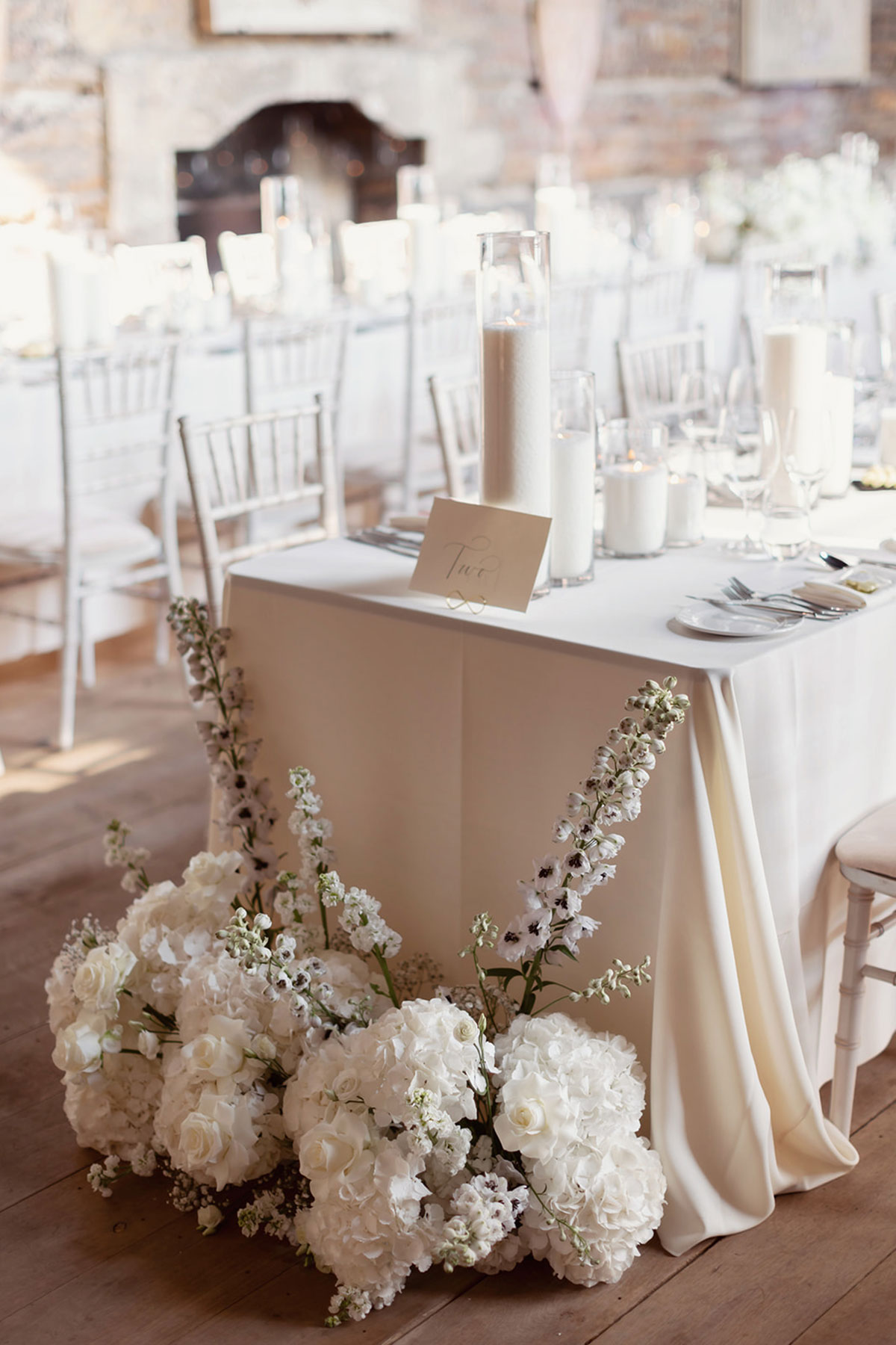 a wedding table with white hydrangea and rose floral arrangement on the floor.