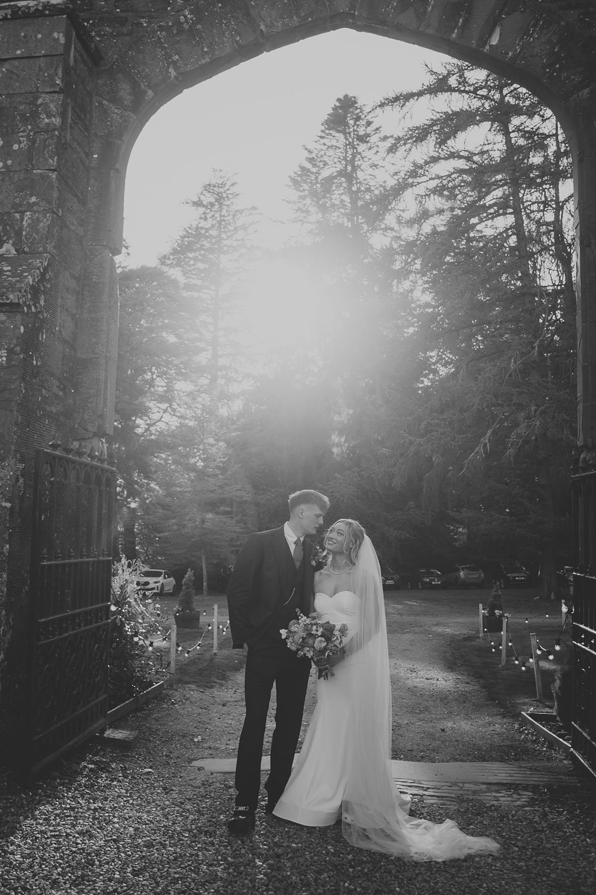 Black and white portrait of bride and groom under stone archway at Rosebery Estate