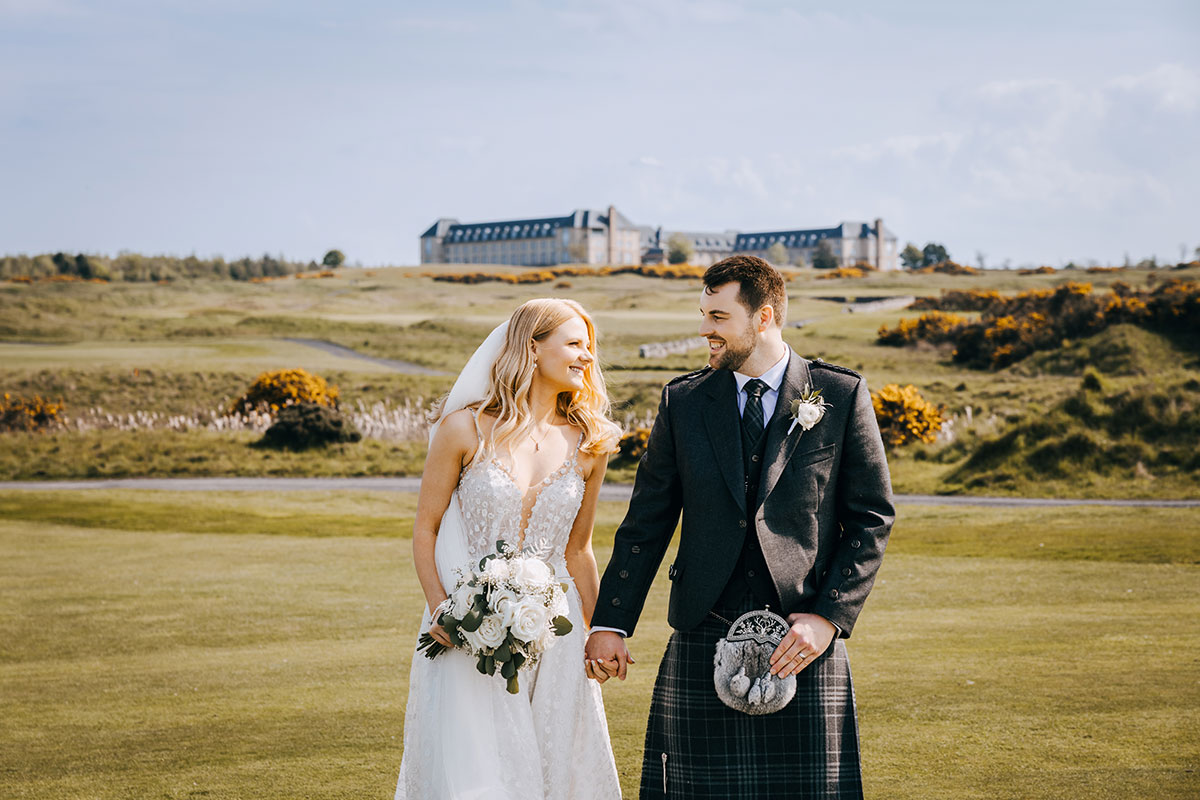Bride and groom outside Fairmont St Andrews with the hotel and golf course in the background