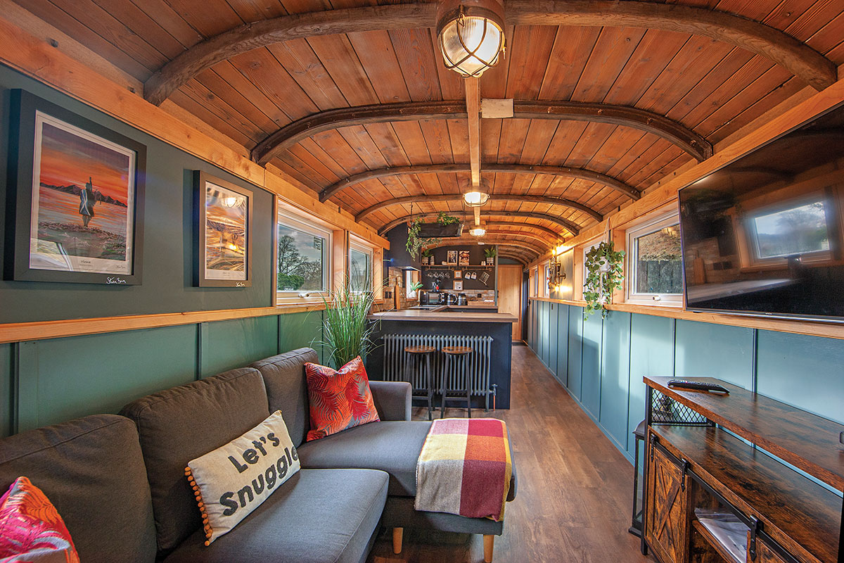 Cosy open-plan living area inside a converted railway carriage at Carriage at Creagan, featuring a lounge, kitchen and vaulted timber ceiling