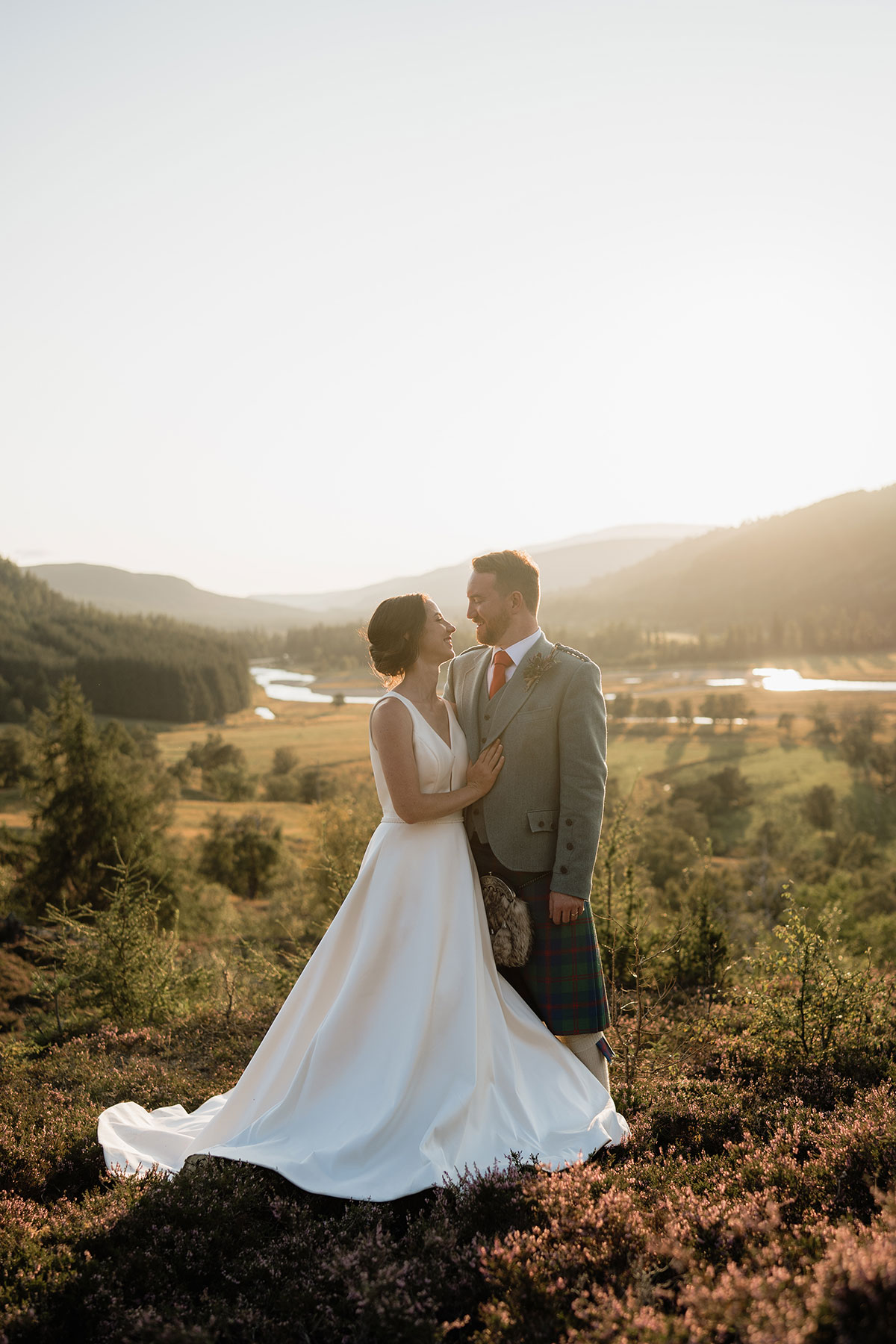 Bride and groom embracing during golden hour wedding portraits overlooking the Cairngorms National Park