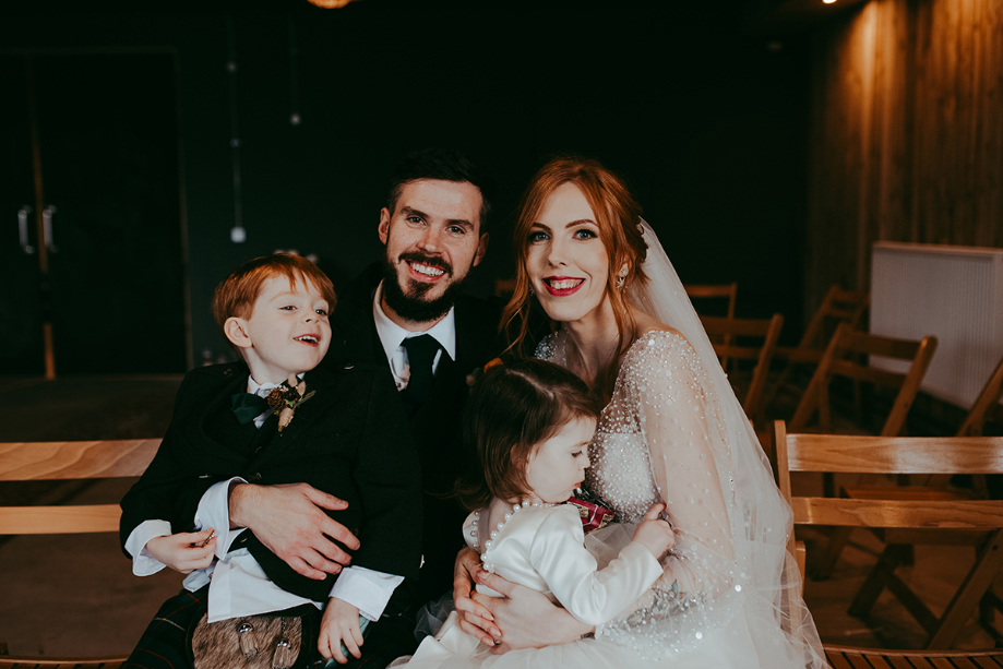 Newlywed couple and their children smile for family portrait