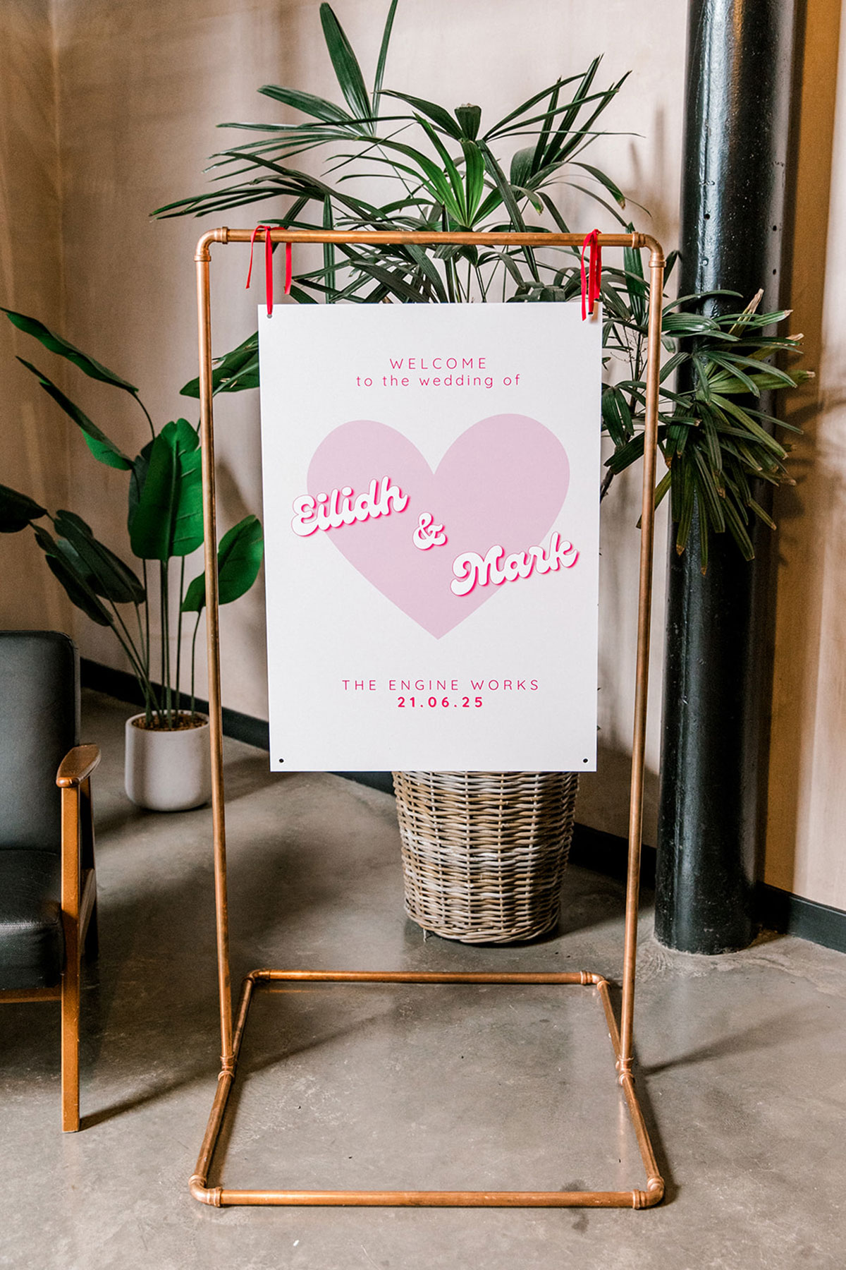 Modern wedding welcome sign featuring a pink heart displayed at the venue entrance