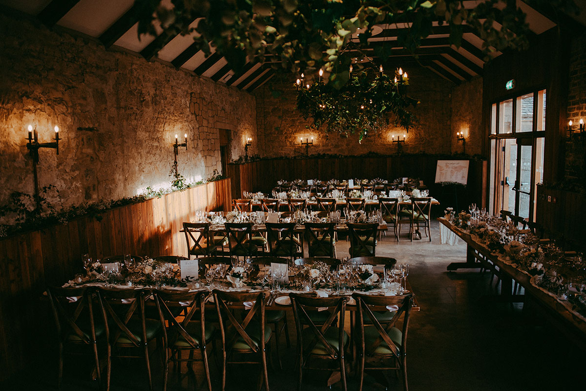 Rustic wedding reception setup at Rosebery Steading with wooden tables, candles and greenery décor