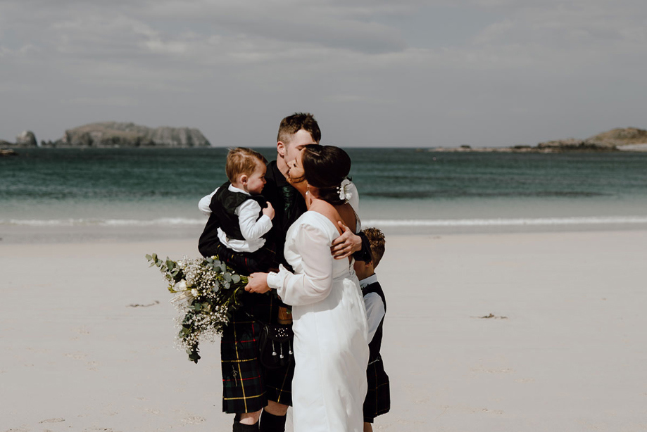 The family share a hug on the beach after sweet first look