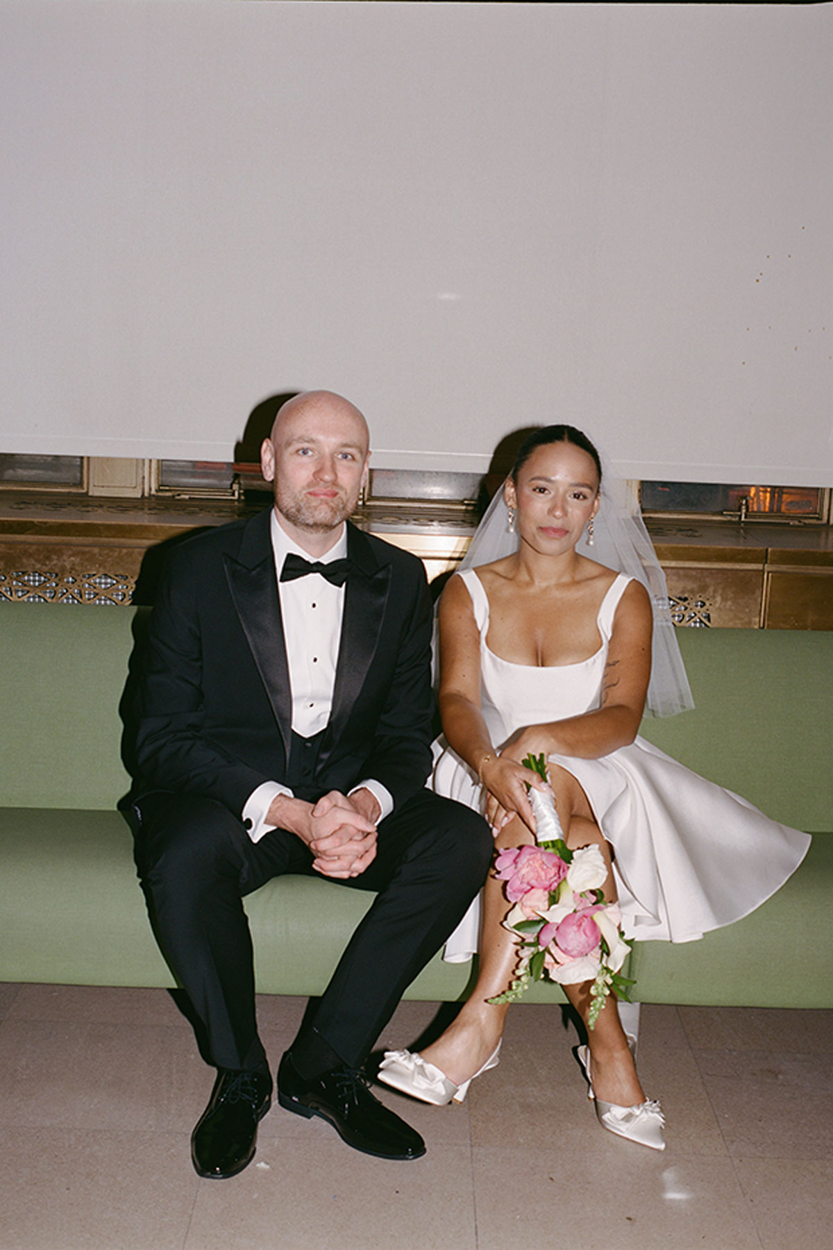 Newlyweds seated together at New York City Hall after elopement ceremony bride in short wedding dress
