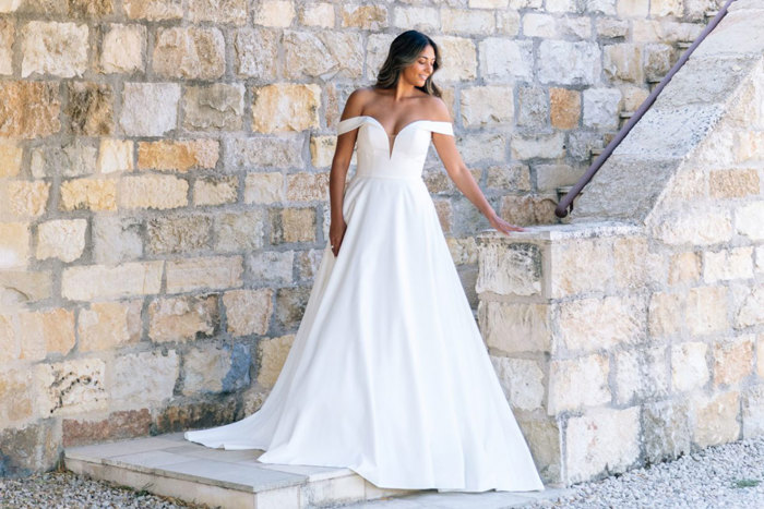 bride stands on stone step at end of outdoor stone staircase wearing an off the shoulder ballgown