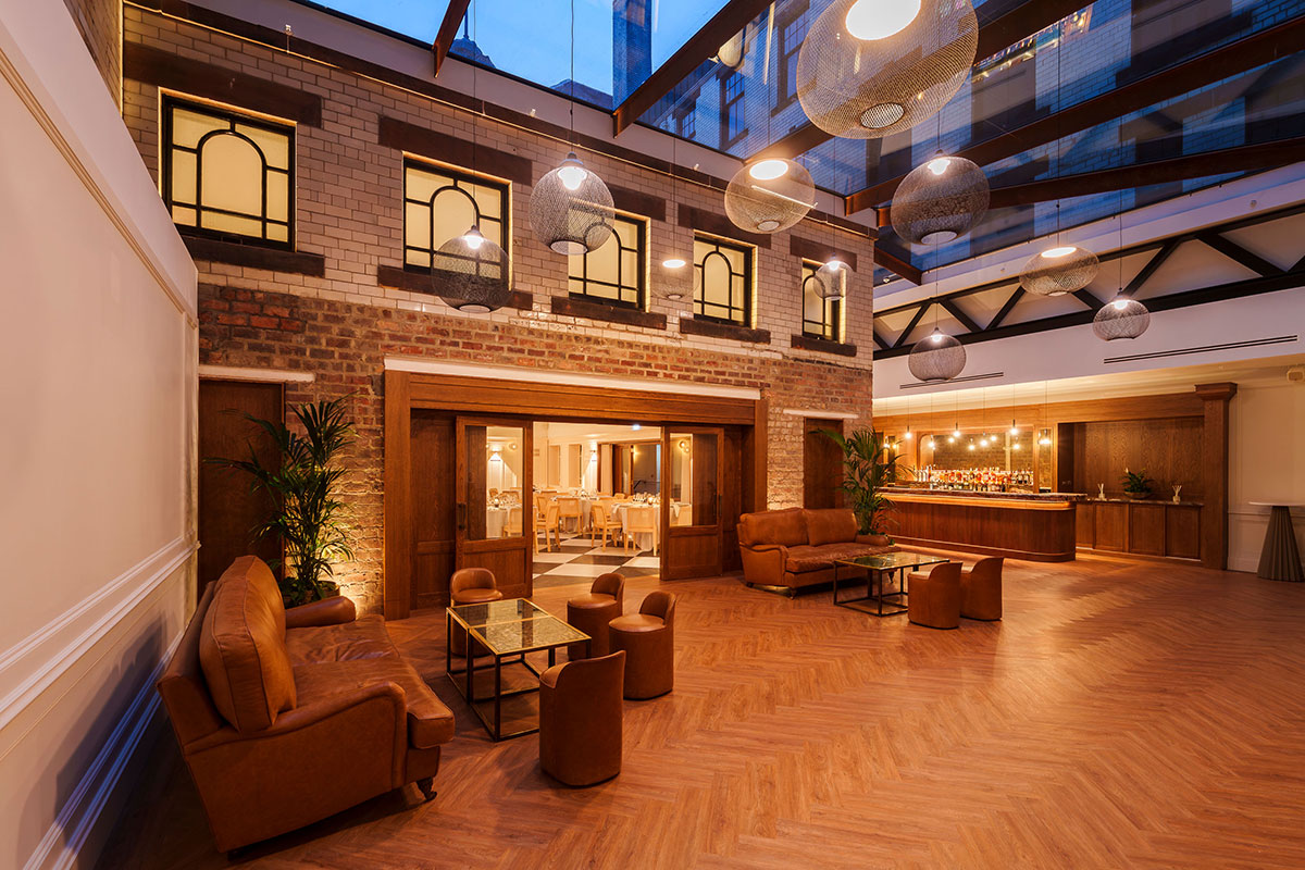 the courtyard at collector's hall at nighttime with brown leather couches, glass ceiling and bar