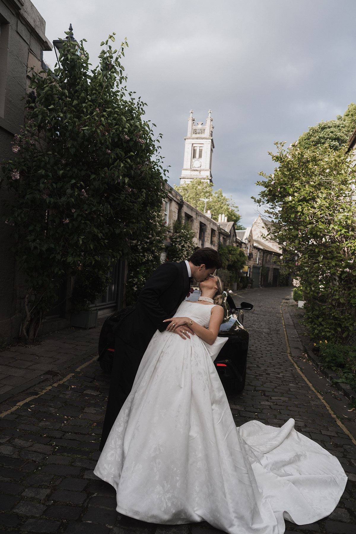 Bride and groom kissing in Edinburgh mews with cobbled street and stone buildings backdrop