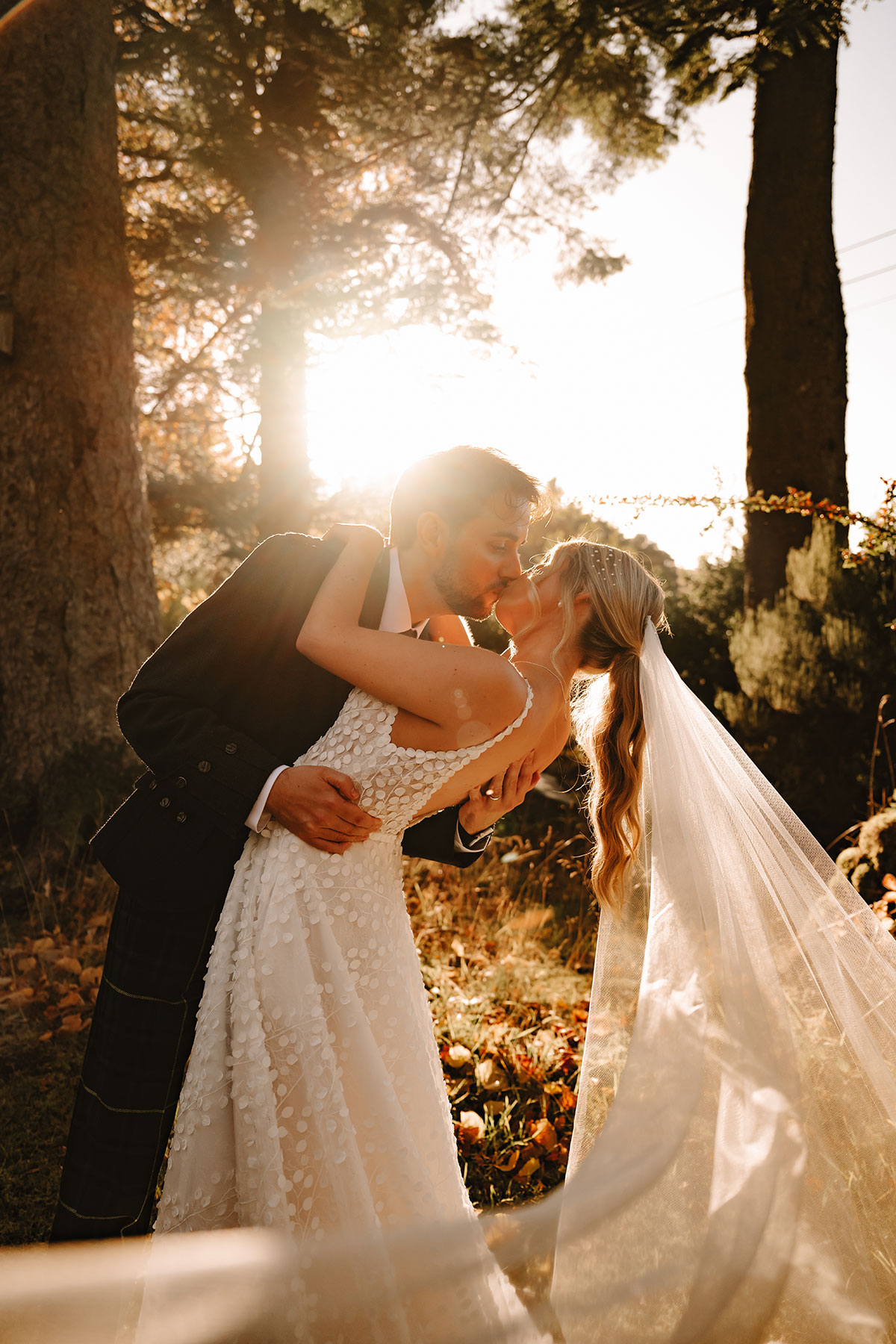 Bride and groom kissing as the sun sets behind them