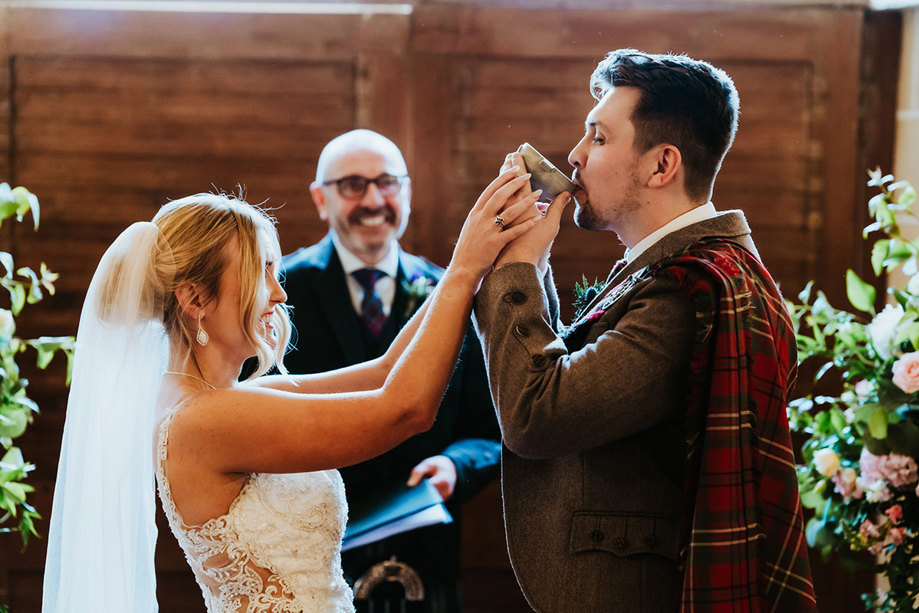 groom drinks from quaich during wedding ceremony at dalhousie castle