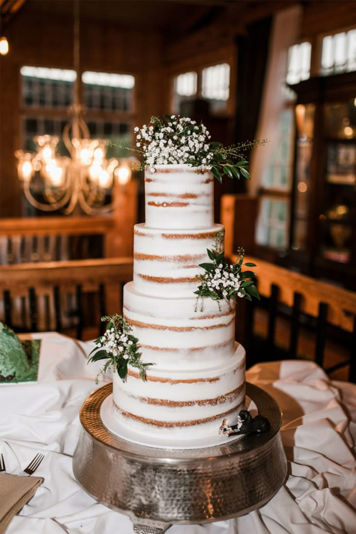 naked wedding cake with four tiers and white flowers