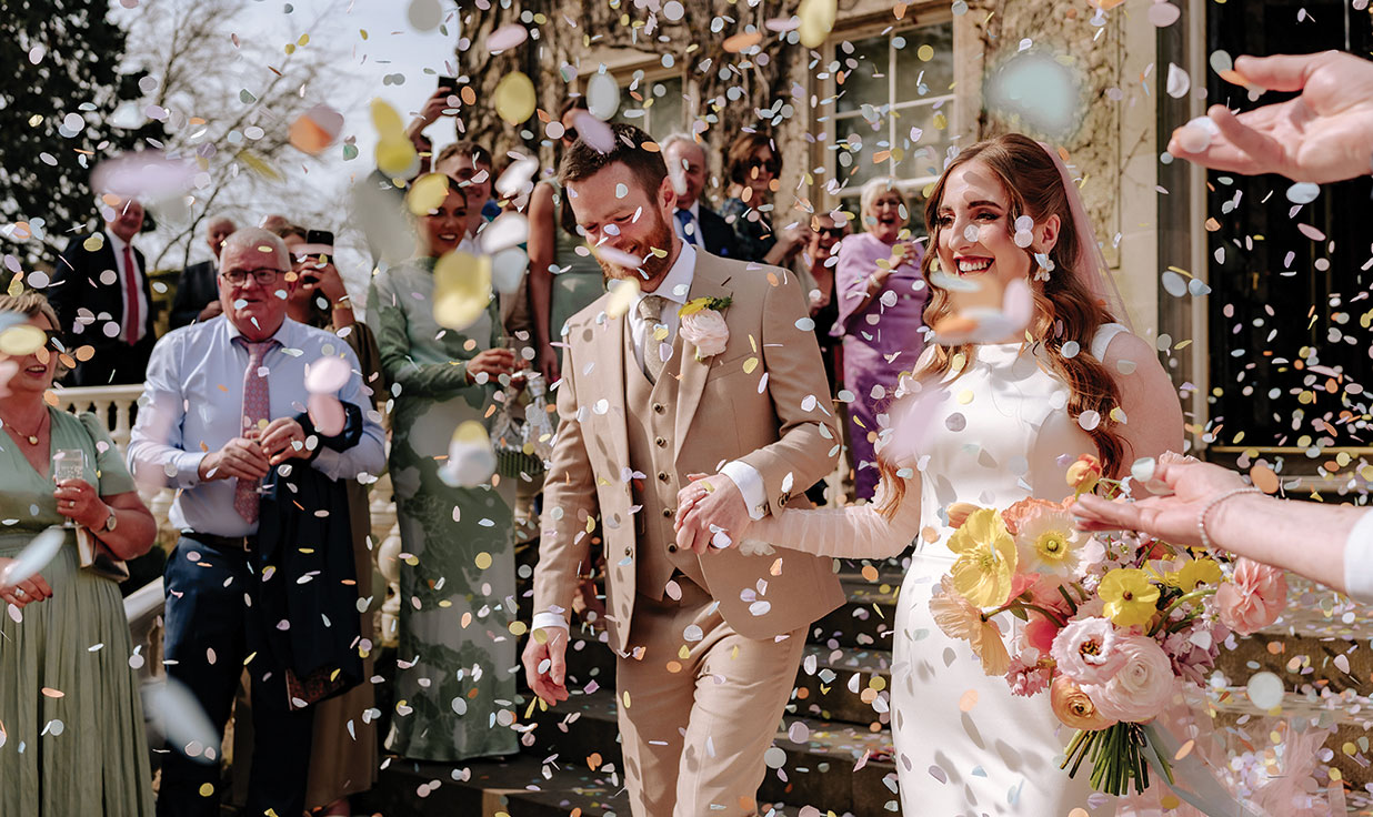 bride and groom smile as guests throw confetti during wedding at carlowrie castle