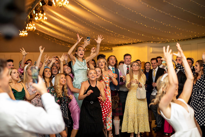 Female guests jump as bride throws the bouquet 