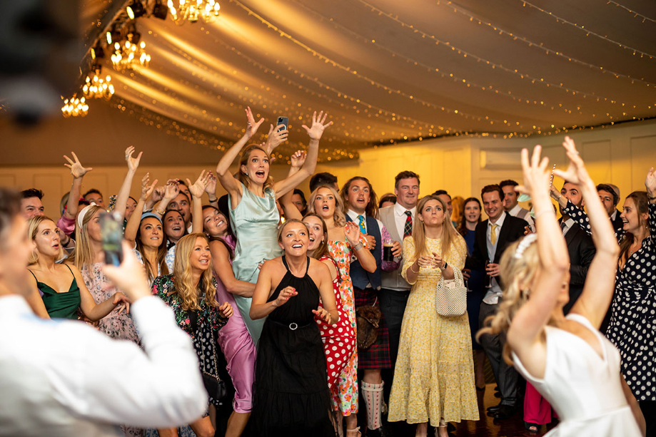 Female guests jump as bride throws the bouquet