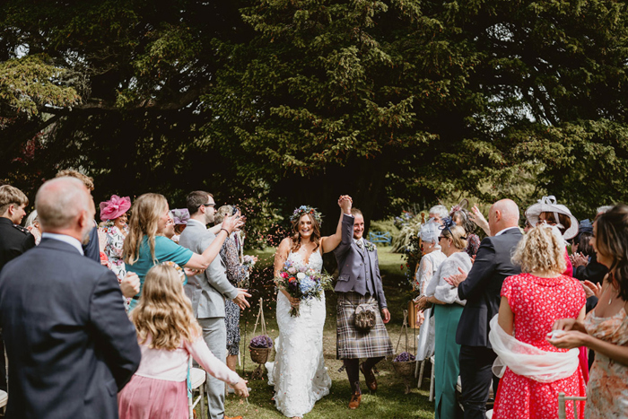 Guests throw confetti at couple as they walk through the crowd